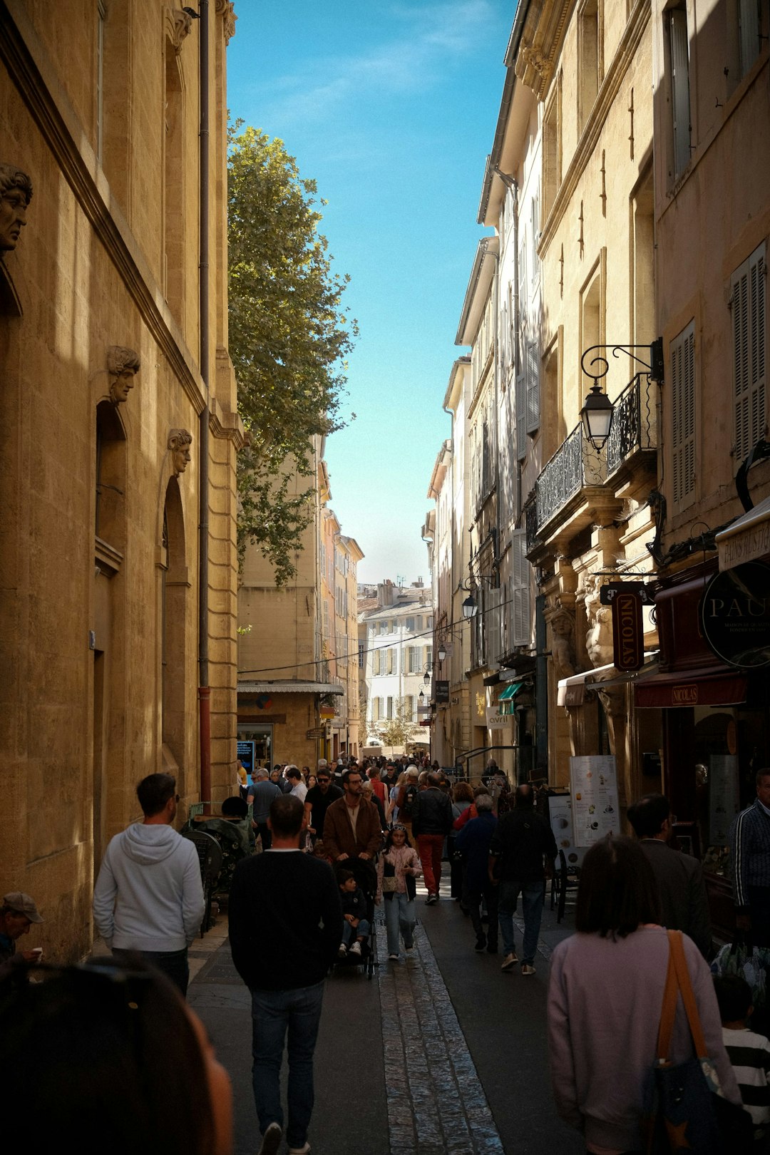 A group of people walking down a street next to tall buildings