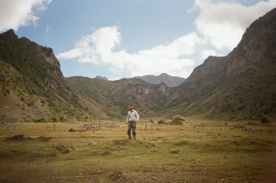 A man standing in a field with mountains in the background